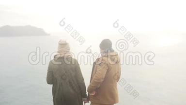 年轻漂亮的夫妇站在海边欣赏风景，转身离去。